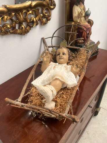 Niño Jesús en Olot, con ojos de cristal sobre cuna de madera.