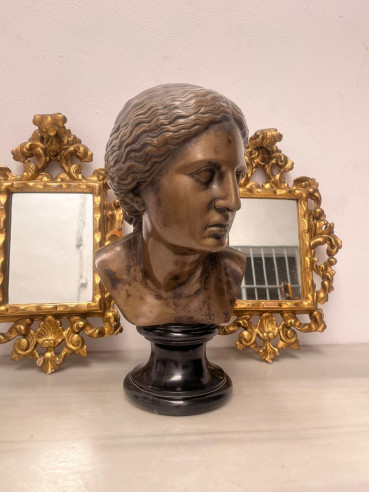 Busto de mujer sobre peana de mármol.